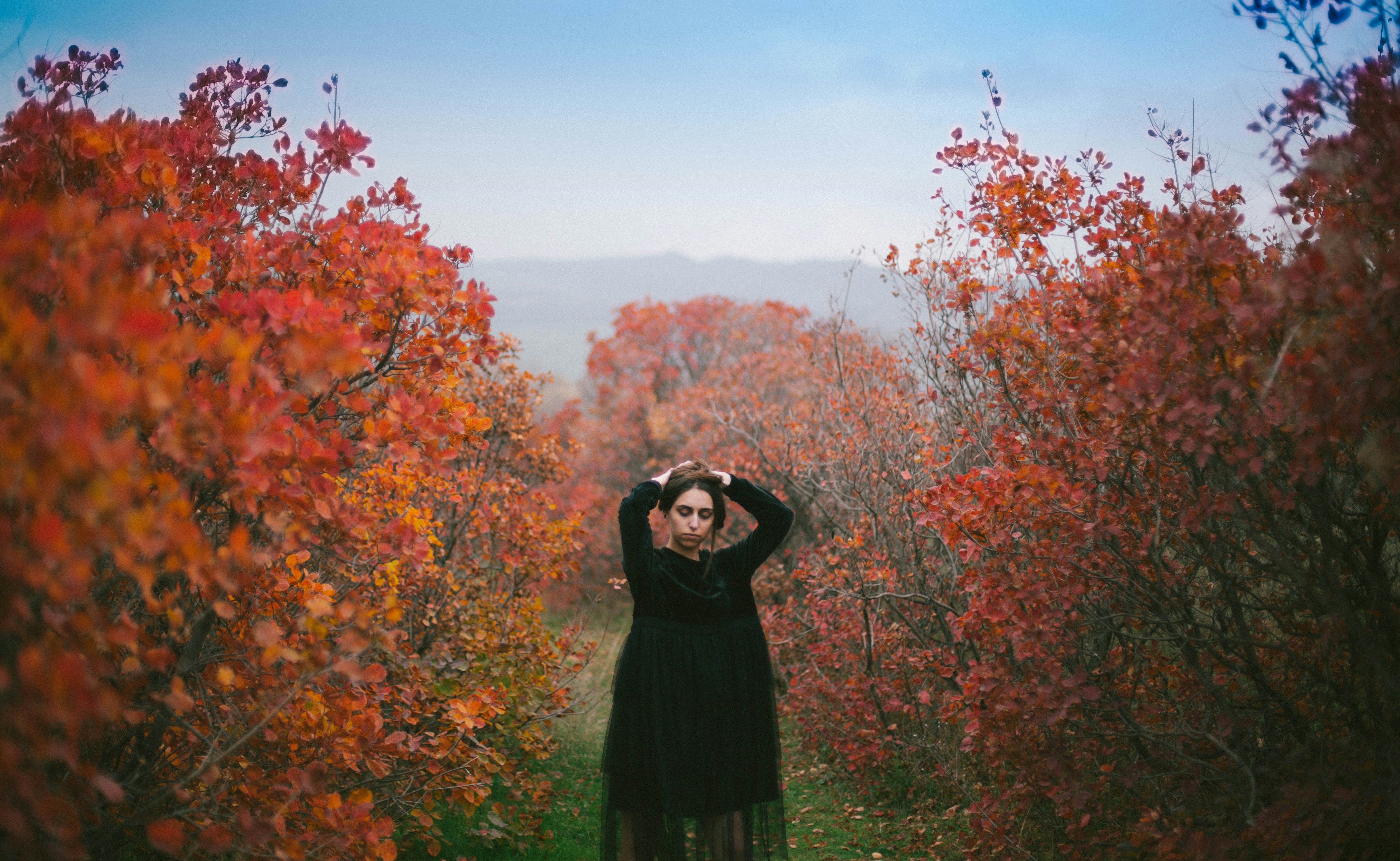 woman standing holding her head between trees